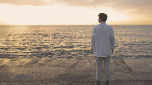 A man walking alone on a quiet beach at sunset, symbolising calm reflection and emotional strength, used in a psychologist-written article with affirmations for him.