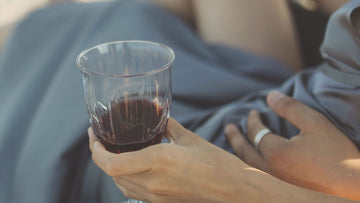 A couple lying together on a quiet beach with glasses of wine, symbolizing emotional closeness, safety, connection and the gentle love-guidance in this psychologist-written Talk2Tessa article.