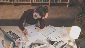 Student studying in a library with books and papers, illustrating focus, stress, and the inner pressure addressed by ACT-based affirmations for students.