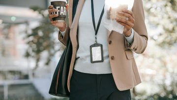 Woman walking through an office area holding coffee and a sandwich, symbolizing work burnout recovery, slowing down, guilt-free rest, ACT-based self-help, self-compassion practices, and AI-guided Prompt Flows from Talk2Tessa.