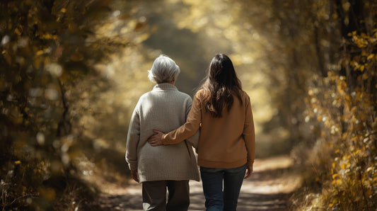 Young caregiver supporting an elderly woman while walking in a calm forest, symbolising caregiver burnout recovery, compassion fatigue, ACT self-help and guilt-free rest with Talk2Tessa.