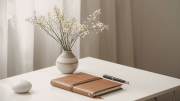 Desk with a closed journal and soft flowers, symbolizing gentle self growth, reflection, and psychologist-designed journaling support by Talk2Tessa.