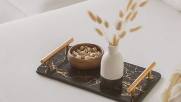 A soft tray on a bed with flowers and a small bowl of nuts, creating a calm, gentle moment of rest and self-kindness.