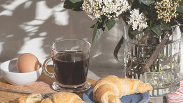 Calm breakfast scene with a journal and warm drink, symbolizing a gentle morning routine and psychologist-written morning journal prompts for emotional clarity.
