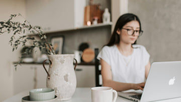 Stock photo of a woman working on a laptop in a calming Japandi-style setting, used to illustrate neurodivergent burnout recovery, ADHD/autistic overwhelm, ACT self-compassion tools, and psychologist-designed support from Talk2Tessa.