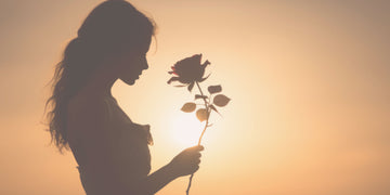 Woman in soft shadow holding a flower — symbolic hero image for a psychologist-written shadow work journaling guide with gentle self-reflection prompts.