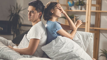 Unhappy couple sitting apart on a bed, showing emotional distance and lack of connection — symbolic image for psychologist-written guide on signs of narcissistic behavior and emotional safety.