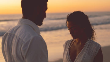 A woman looking thoughtful while standing with her partner on the beach, symbolizing emotional doubt and loss of safety in a relationship — Talk2Tessa psychologist-written guide.