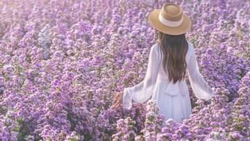 Woman standing in a soft flower field, looking calm and grounded — gentle, warm imagery used for a psychologist-written confidence and self-compassion article by Talk2Tessa.