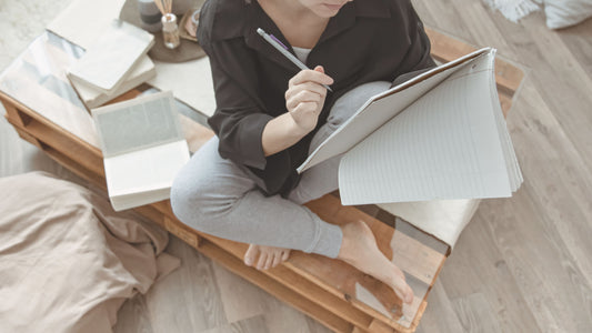 Calm image of a woman writing in a notebook, representing gentle journaling and emotional reflection for the Talk2Tessa guide on journal prompts for beginners.