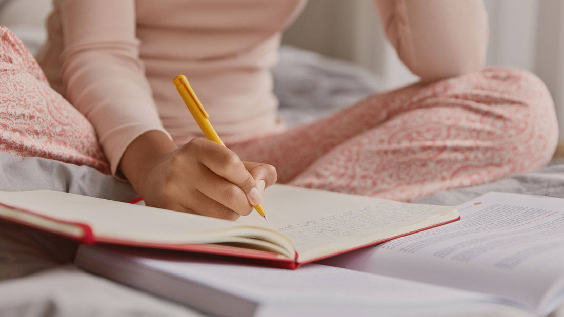 Woman writing in a journal in a calm, soft-lit setting, representing daily journaling for emotional clarity and self-reflection in a psychologist-written guide.