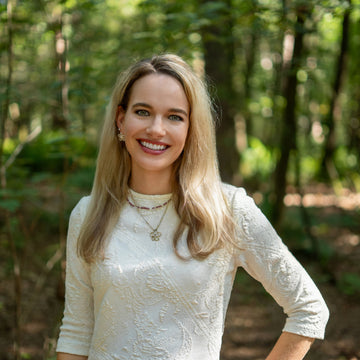 Portrait of Tessa, MSc Psychologist and founder of Talk2Tessa, standing in a forest wearing a white dress, offering gentle and compassionate self-help guidance.
